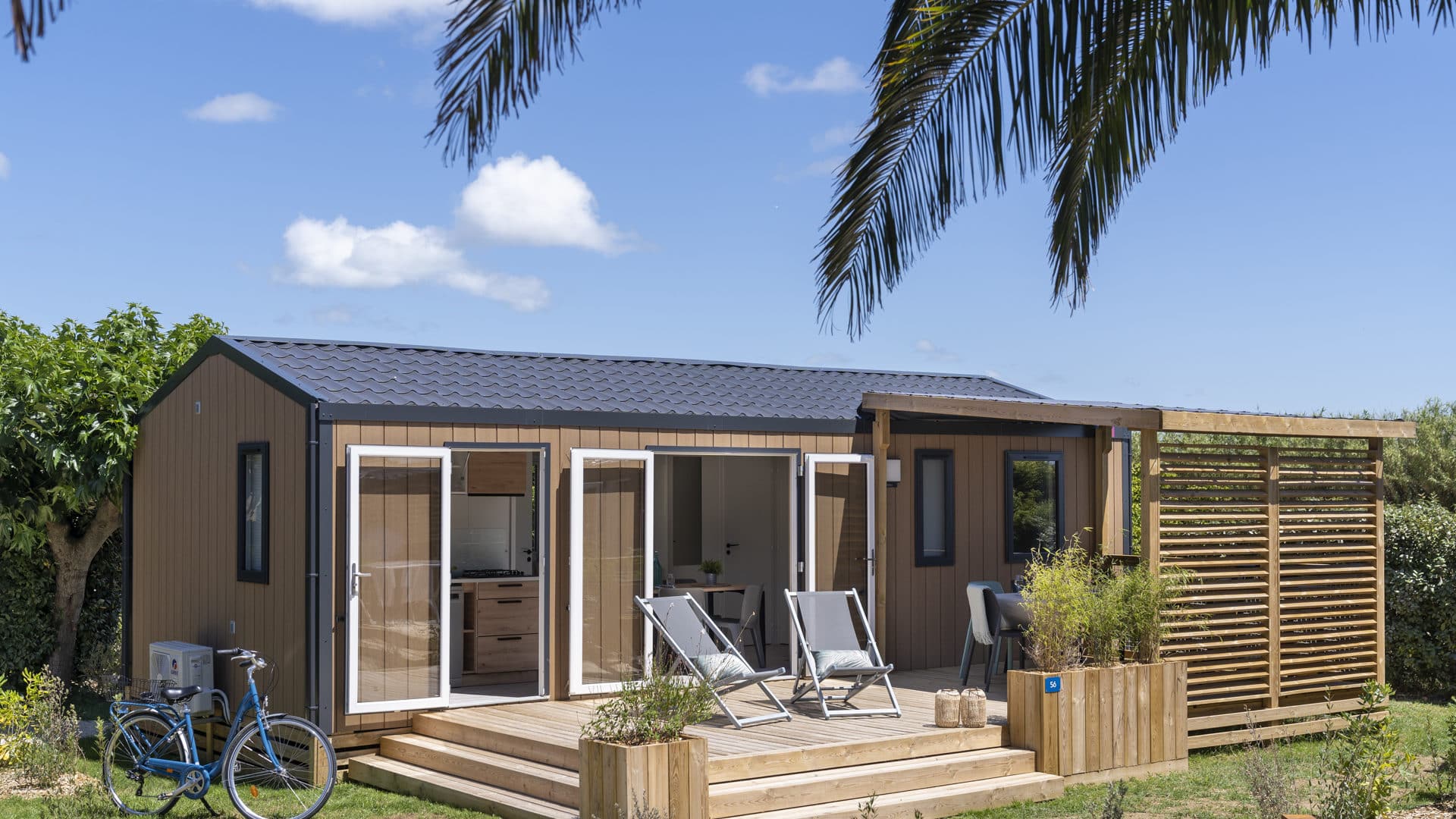 Houten chalet met terras en ligstoelen.