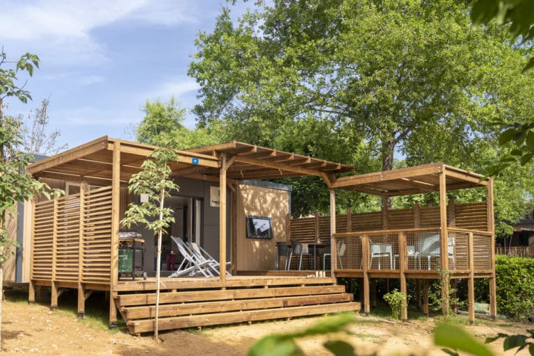 Chalet en bois moderne avec terrasse, jardin verdoyant.