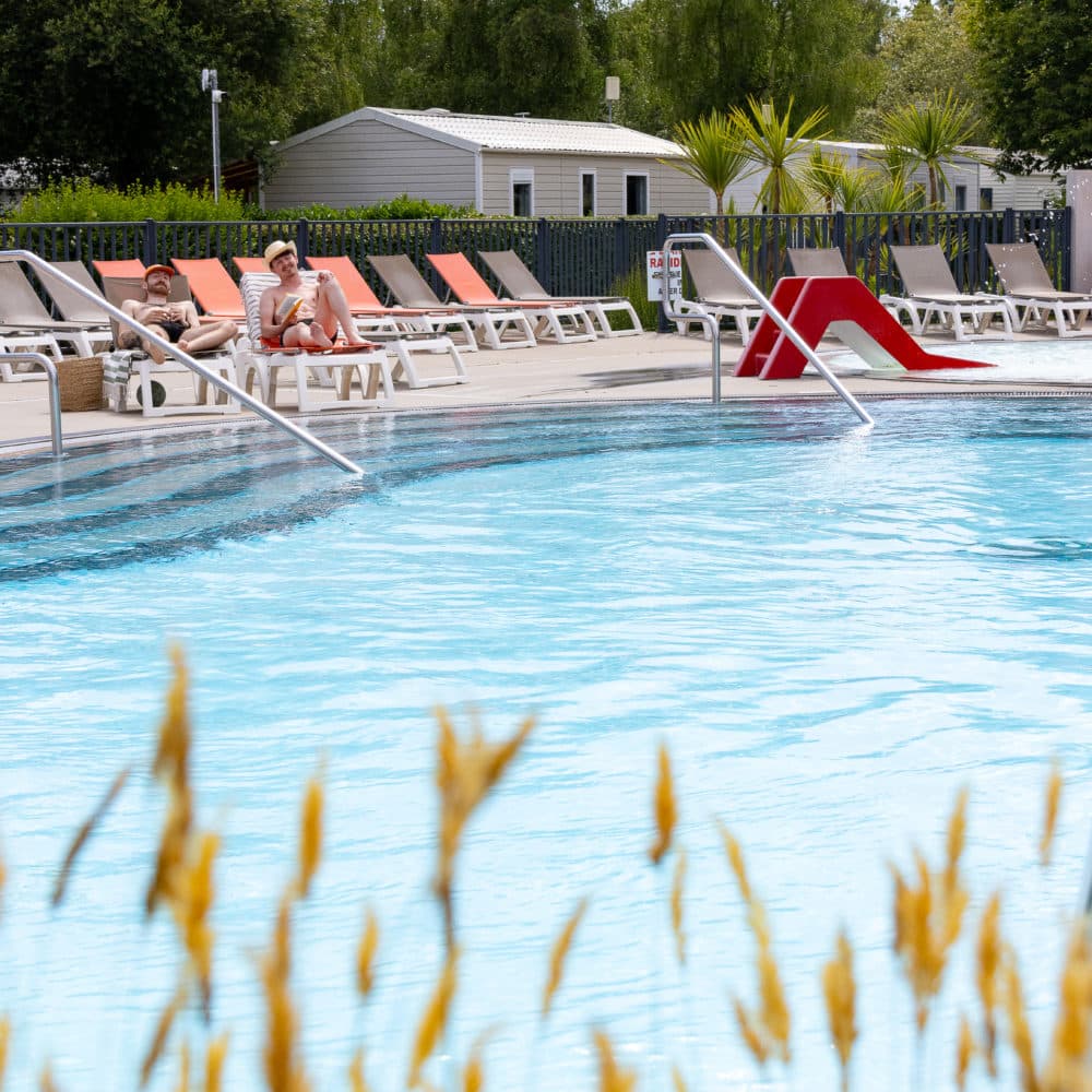 Piscine extérieure avec transats et toboggan rouge.